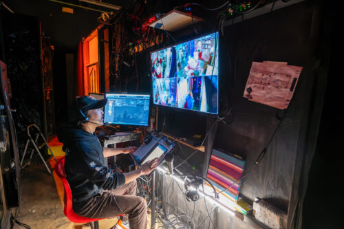 person sits in chair and looks at screen with images of stage scenes
