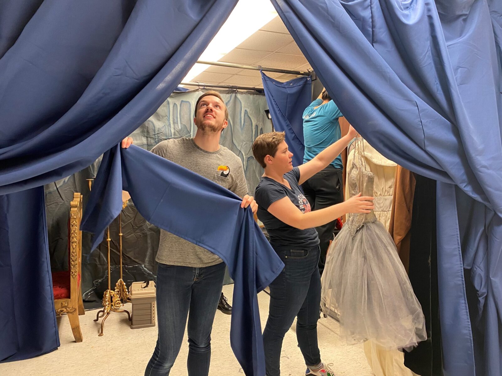 two people hold up costumes and fabric