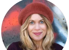 person with orange hat looks at camera standing in front of colorful wall