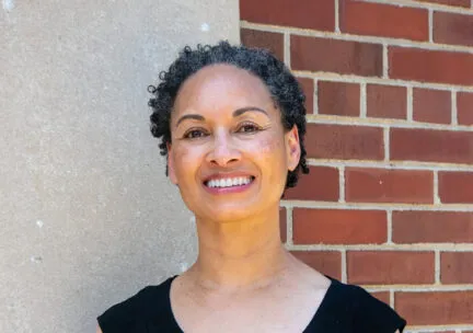 rebecca ginsburg stands in front of brick wall smiling