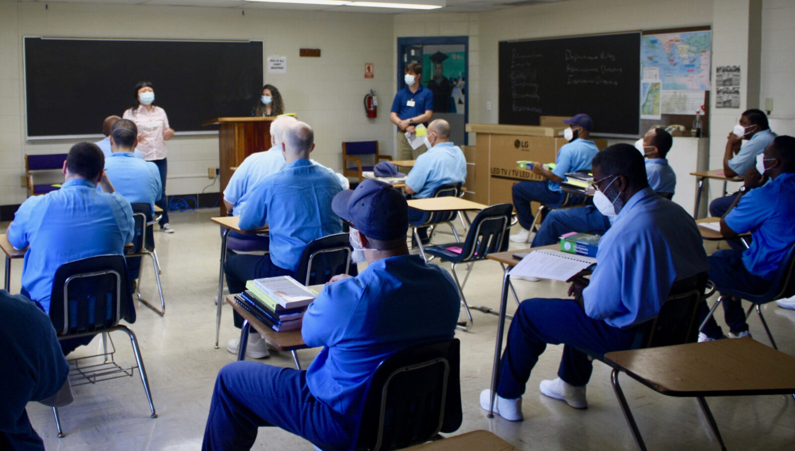 Many desks filled with people in blue shirts from behind