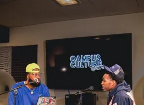 two people sitting at table talking into mics