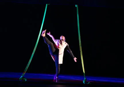 a dancer onstage kicks legs up