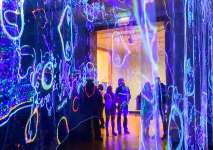 colorful light projections in a dark room with people watching