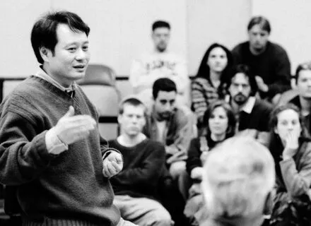 person speaks with arm raised to a group of people