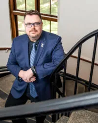 Dean Pinholster leans on a railing in a stairwell