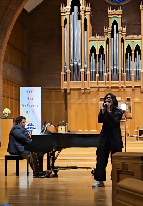 alonza plays piano while someone sings into a mic