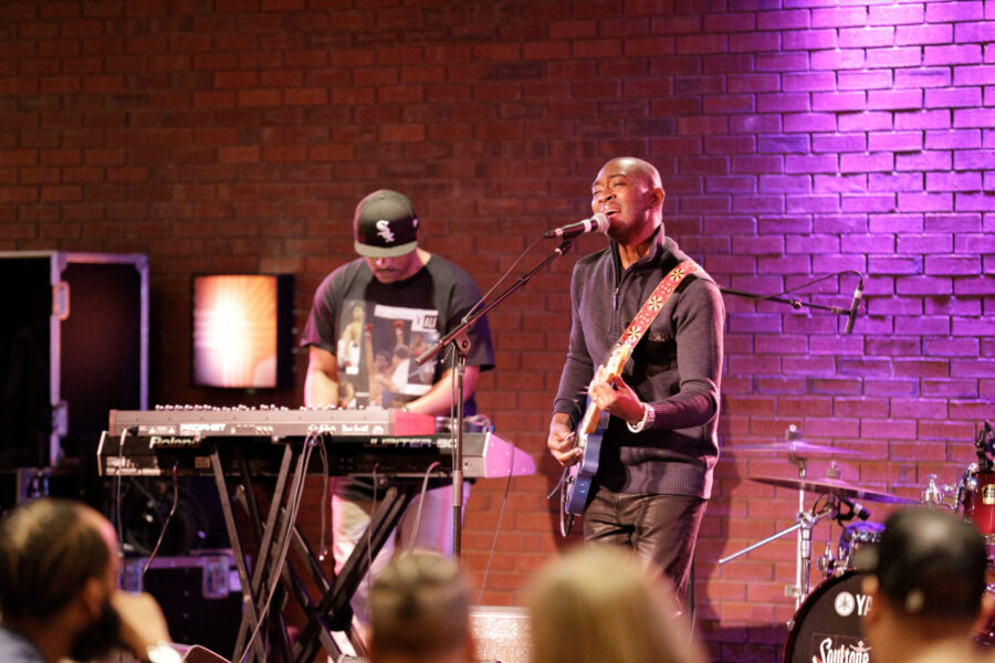 man singing and playing guitar on stage with keyboardist